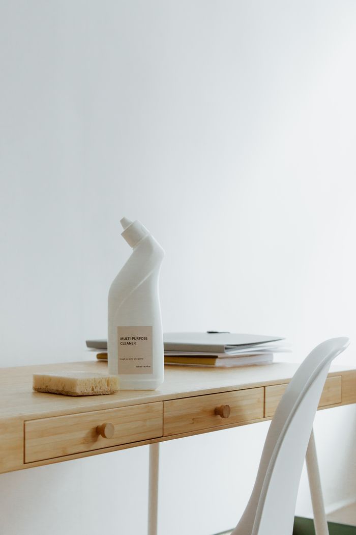 journey-02 A clean and organized home office desk with a cleaner bottle and sponge, emphasizing simplicity and functionality.